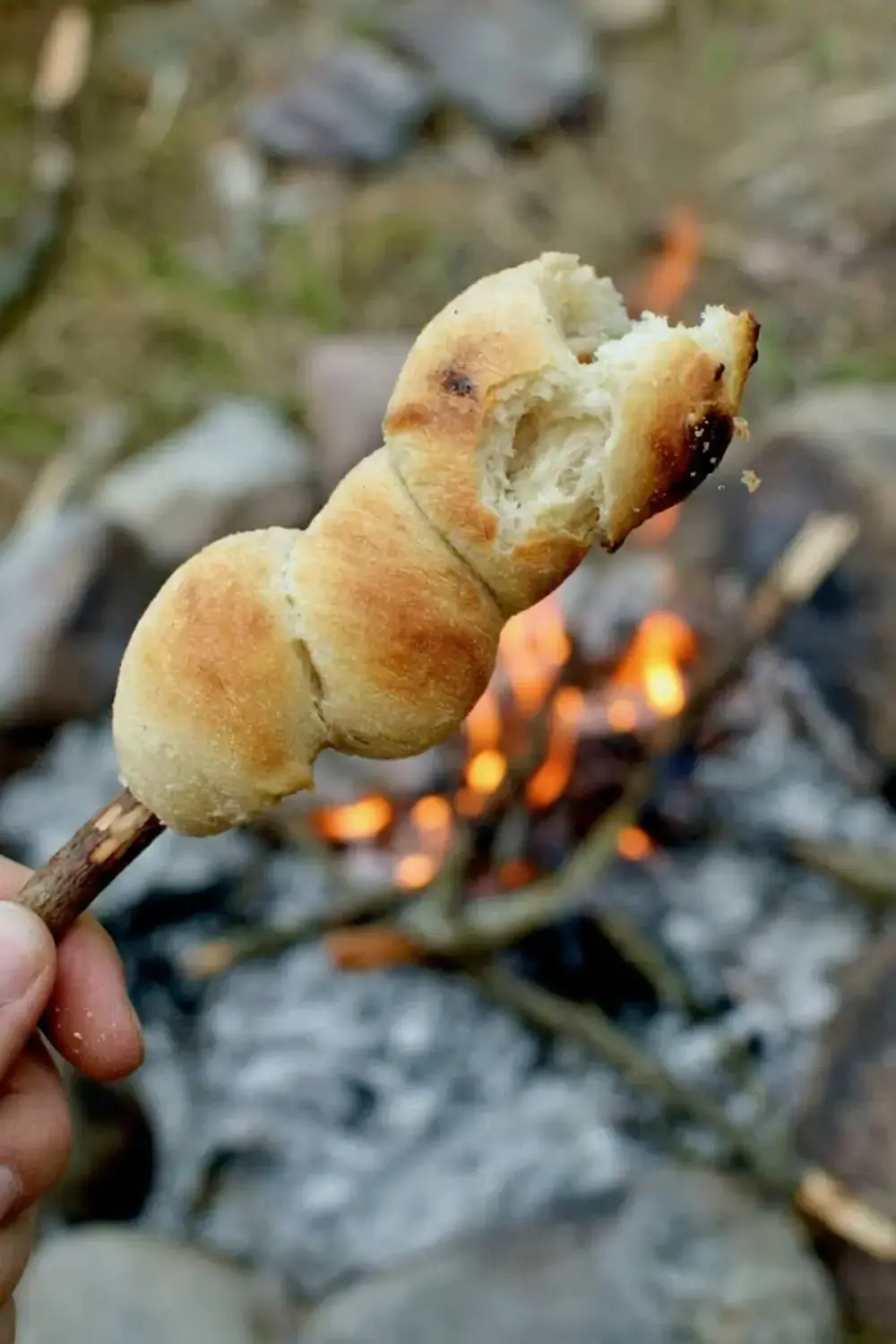 Bread sticks positioned over glowing campfire embers
