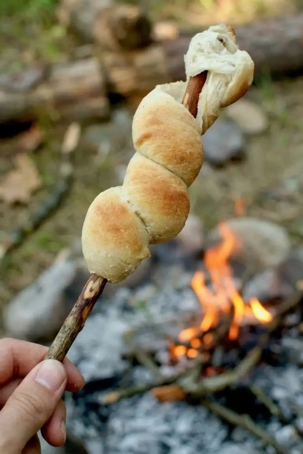 Stickbread browning evenly over glowing coals