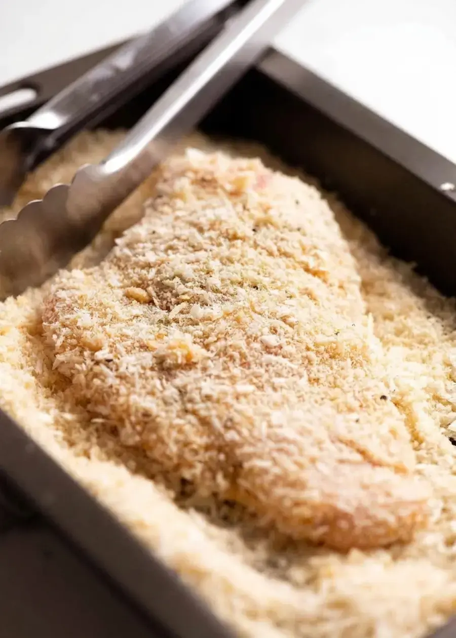 Chicken pressed firmly into panko Parmesan crumbs