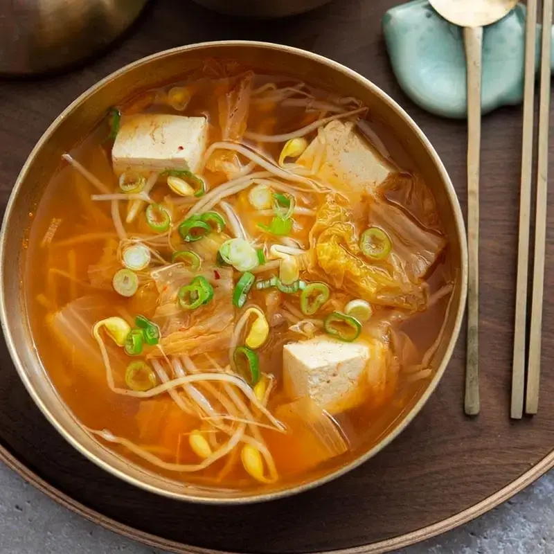 A bowl of kimchi bean sprout soup with tofu and green onion
