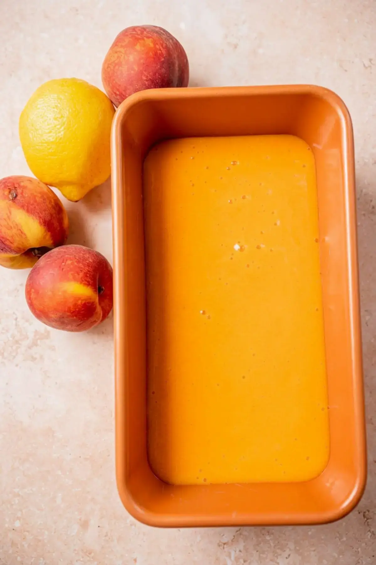 Smooth peach mixture poured into a metal loaf pan